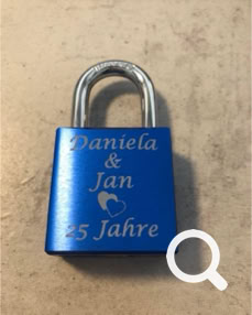 Blaues Liebesschloss mit einer Gravur in Zwei Zeilen und verschlungenen Herzen