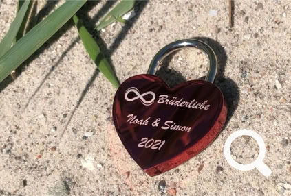 Rotes Liebesschloss mit einem Unendlichkeitszeichen und einer Namensgravur von Zwei Brüdern